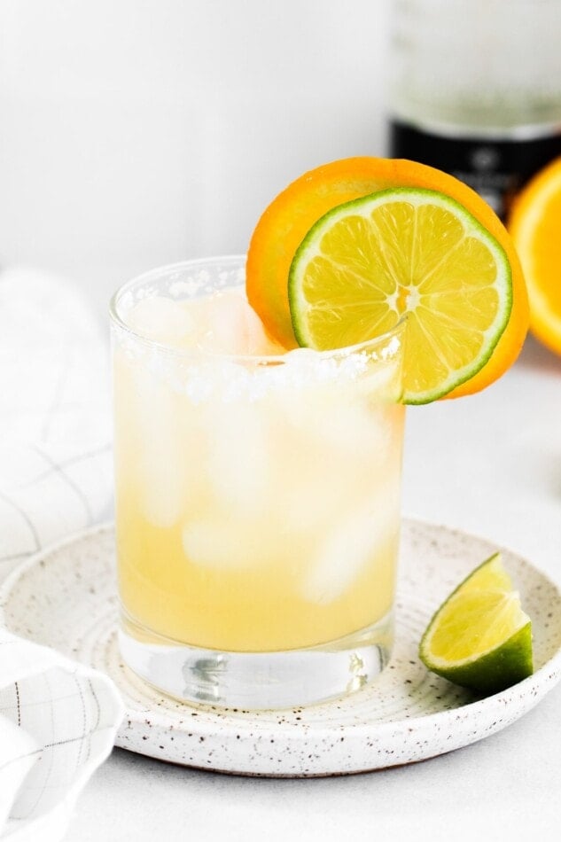 Glass of a skinny margarita with slices of lime and orange.