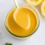 Spoon with tahini dressing from a jar.