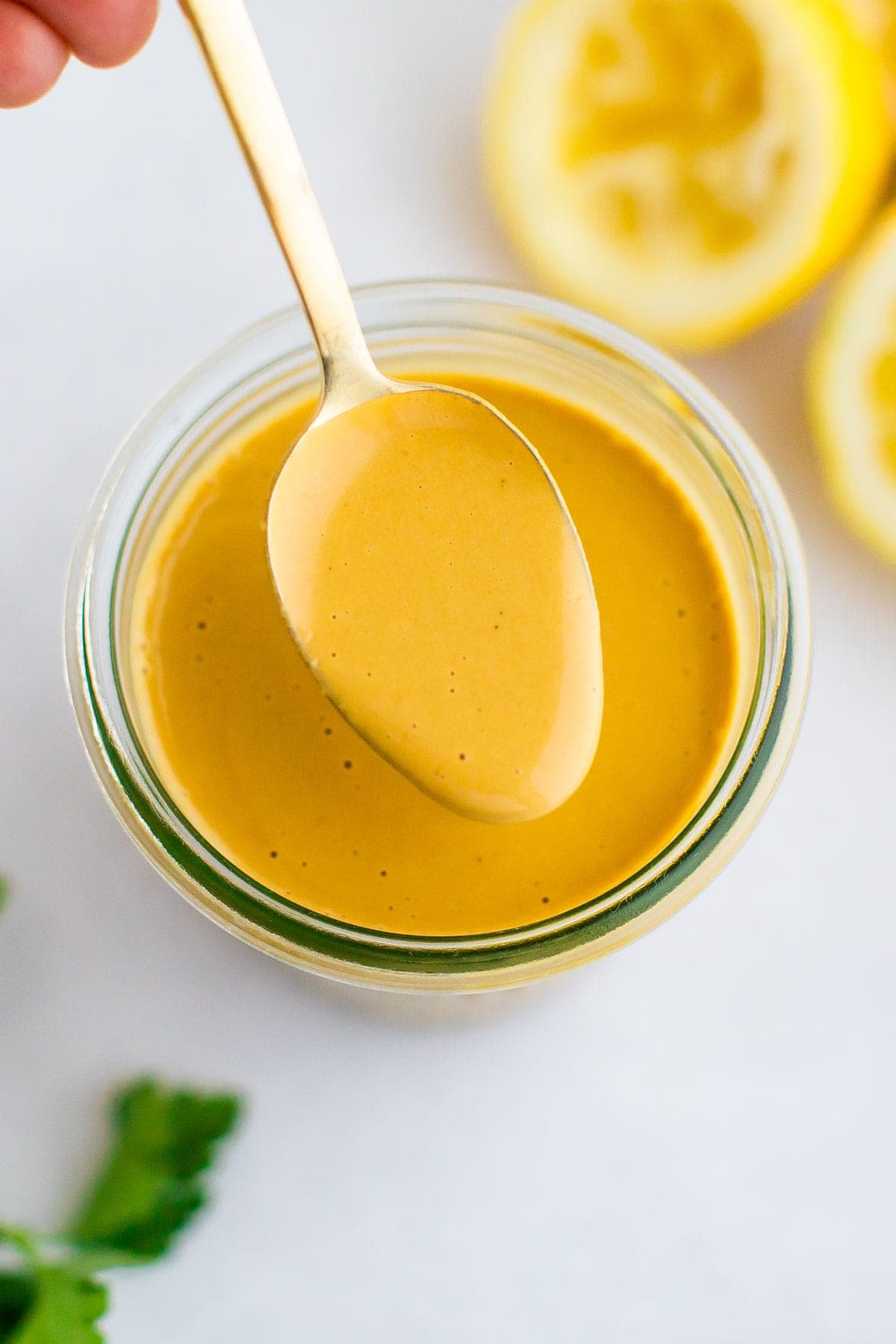 Spoon with tahini dressing from a jar.