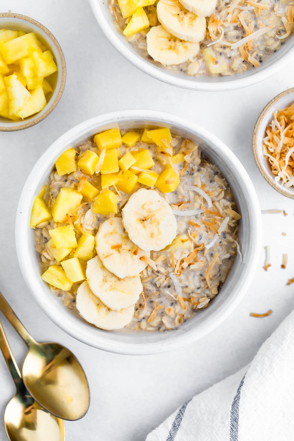 Bowl of overnight oats topped with pineapple, mango, coconut and banana