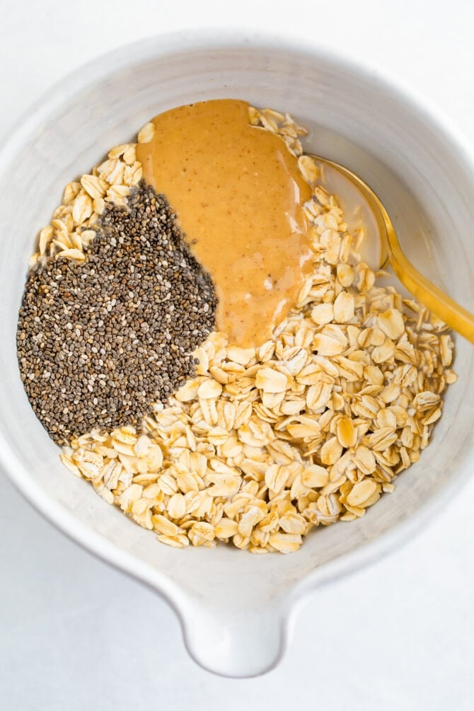 Mixing bowl with oats, peanut butter, chia seeds and almond milk.