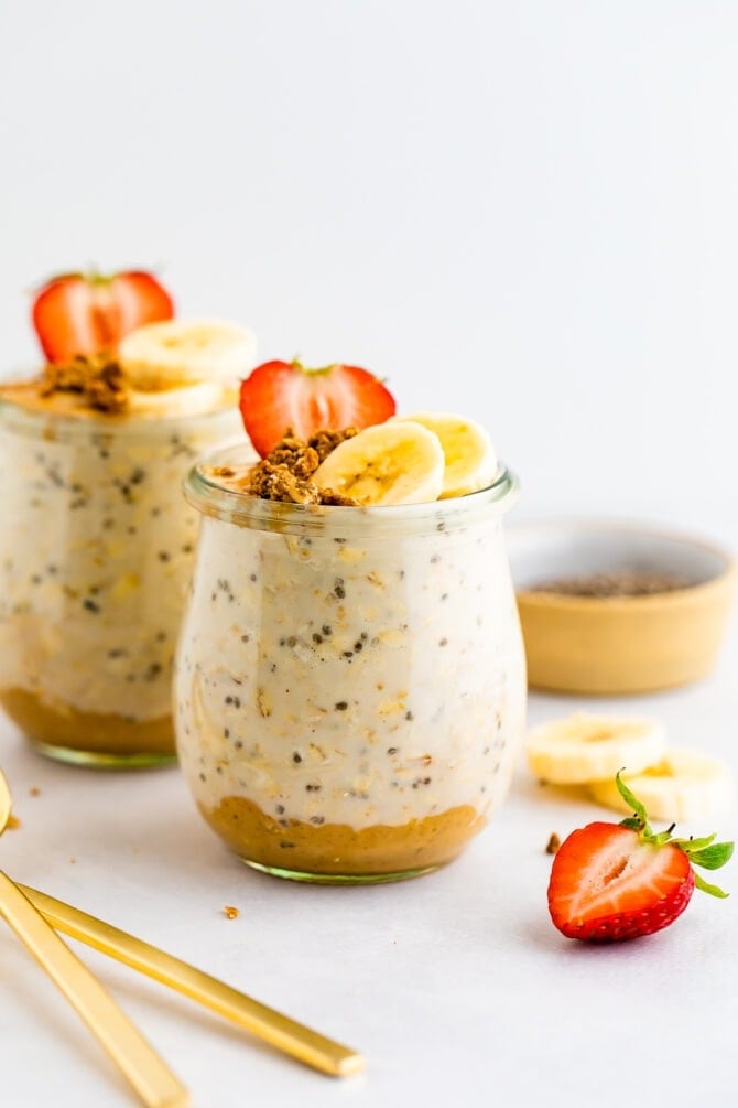 Two jars of overnight oats. The bottom as peanut butter and it's topped with fruit and granola.