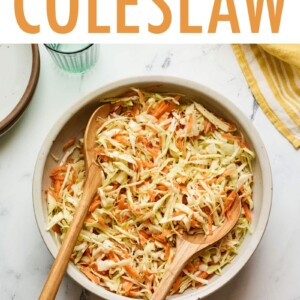 Serving bowl of apple cider vinegar coleslaw with wood serving spoons.