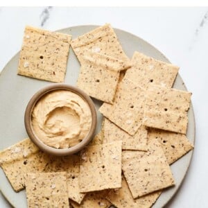 Plate of almond flour crackers with a bowl of hummus.