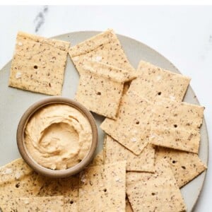 Plate of almond flour crackers with a bowl of hummus.