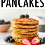 Stack of almond flour pancakes served with berries and maple syrup.