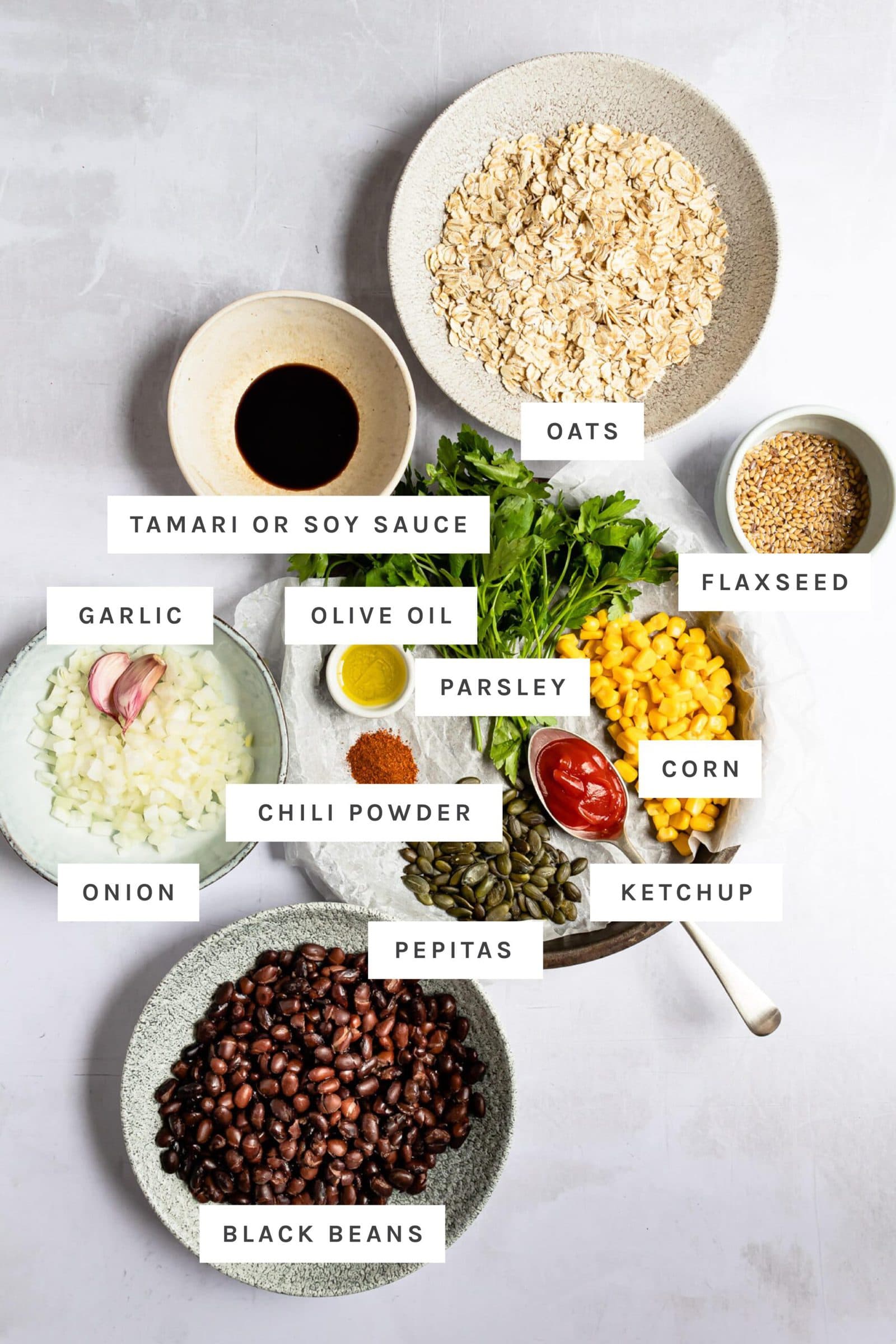 Ingredients to make black bean burgers with labels including beans, veggies, oats and spices.