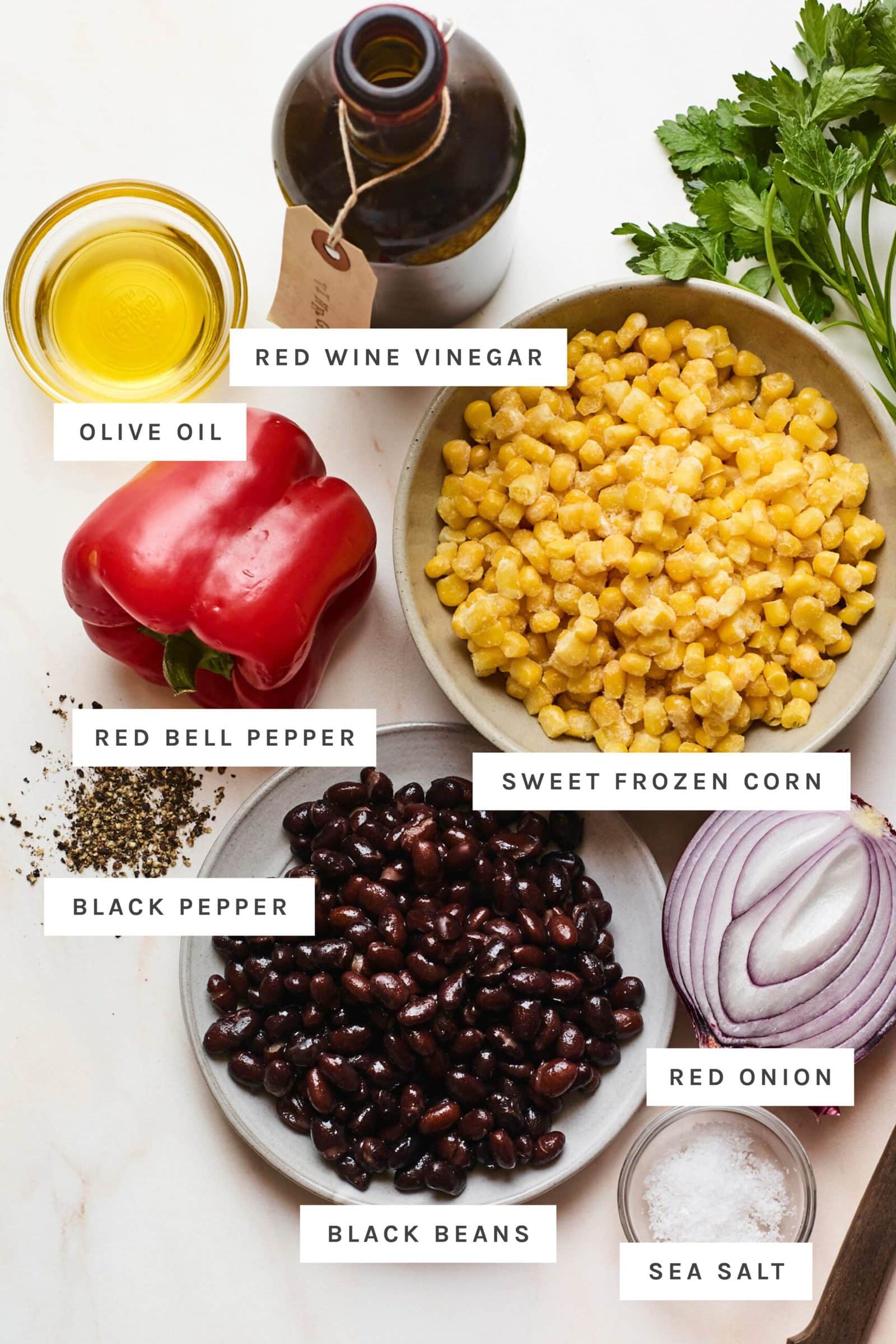 Ingredients measured out to make black bean corn salad: oil, vinegar, corn, pepper, onion, black beans, salt and pepper.
