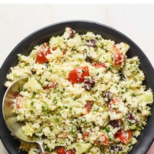 Serving bowl of cauliflower tabbouleh with a serving spoon.