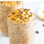 Coffee overnight oats in a mason jar and topped with peanut butter and cocoa nibs.