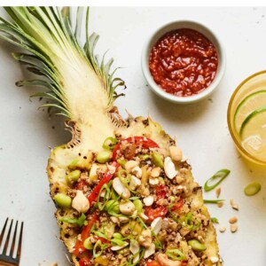 Pineapple boat full of pineapple fried quinoa. Bowl of garlic chili sauce is next to the pineapple.