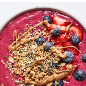 Smoothie bowl topped with berries, granola and almond butter.