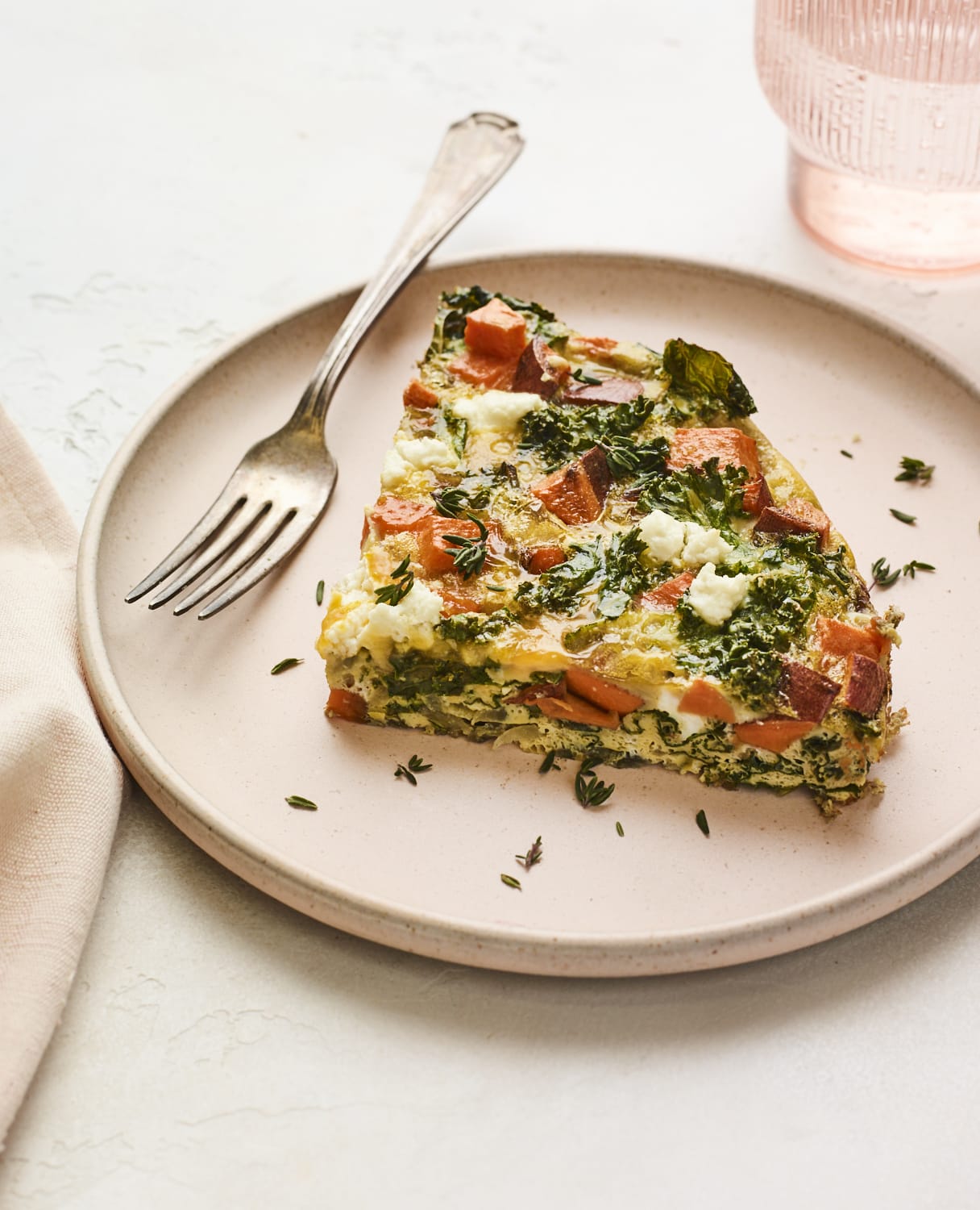 Slice of sweet potato kale frittata on a plate with a fork.