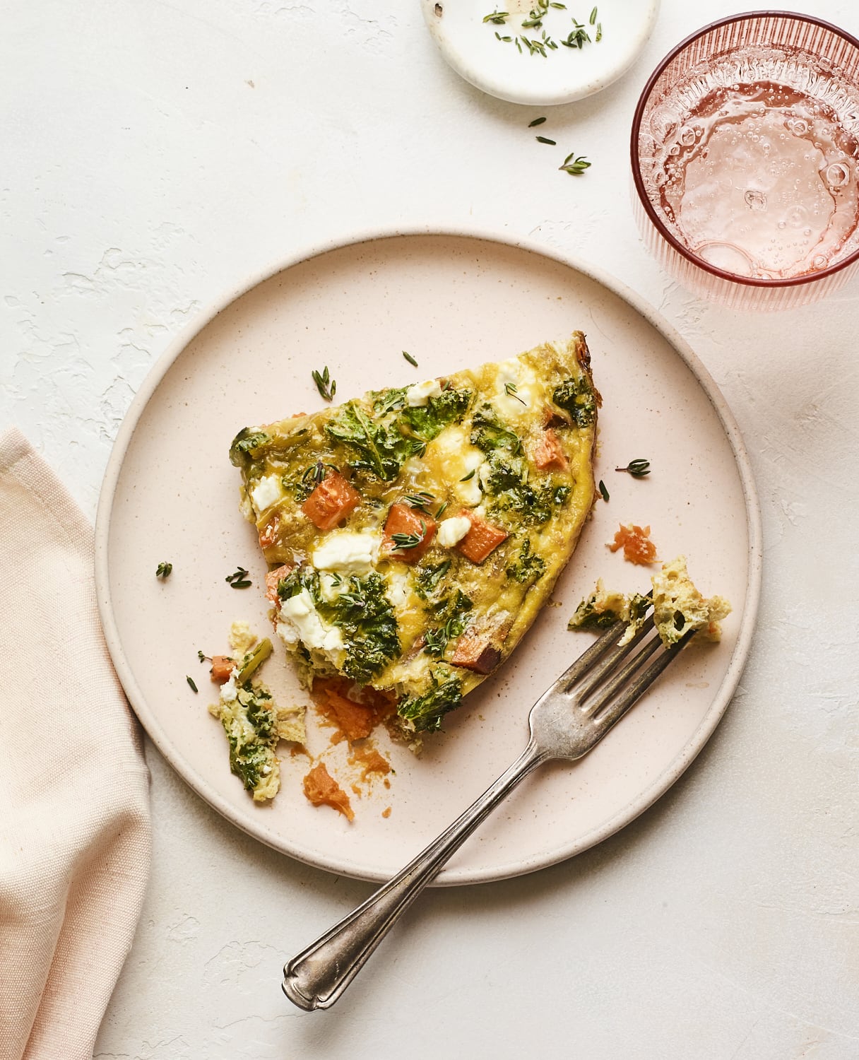 Slice of sweet potato kale frittata on a plate with a fork. A bite it taken out.