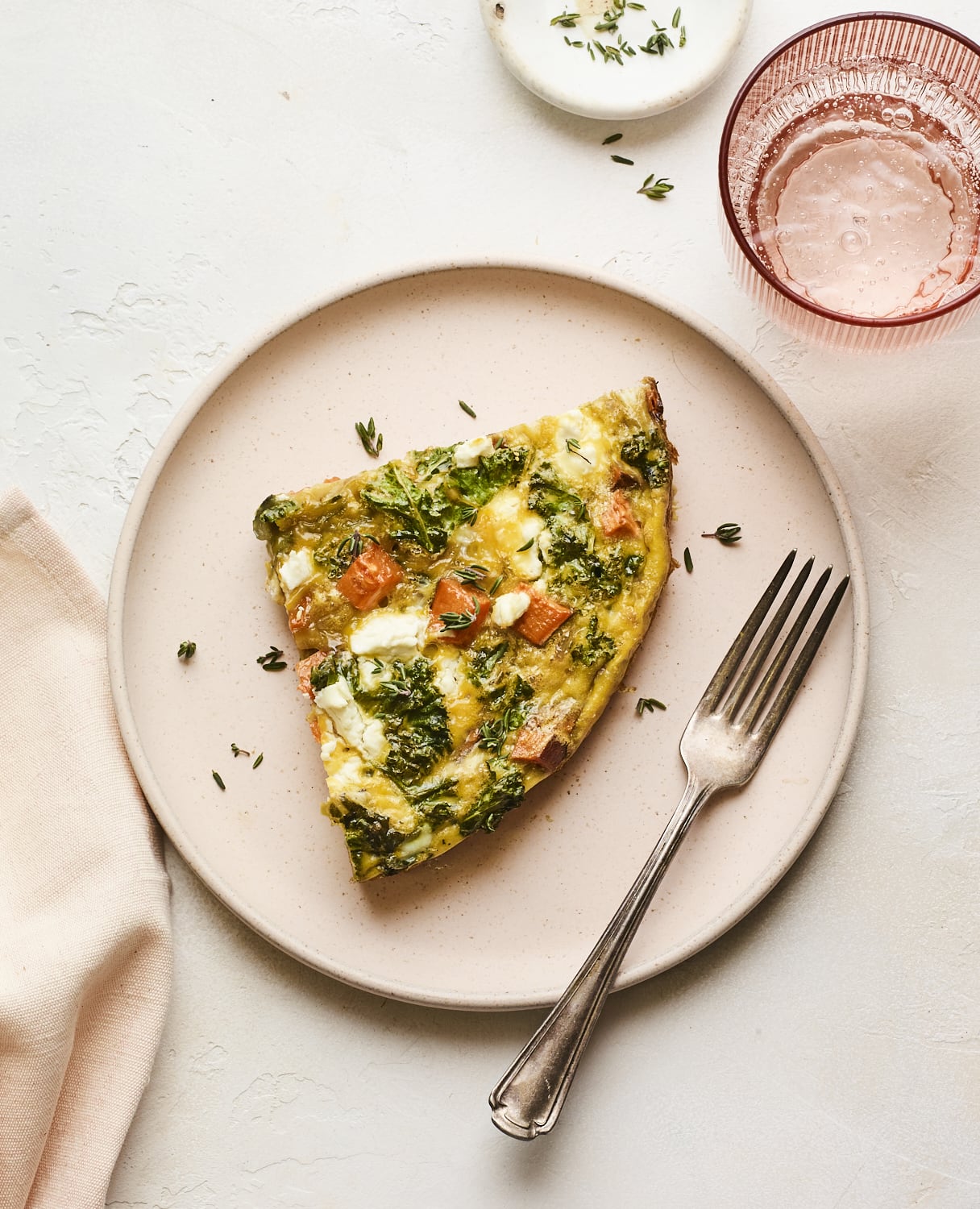 Slice of sweet potato kale frittata on a plate with a fork.