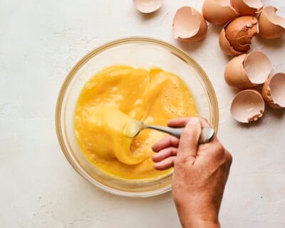 Whisking eggs in a large bowl with a fork.