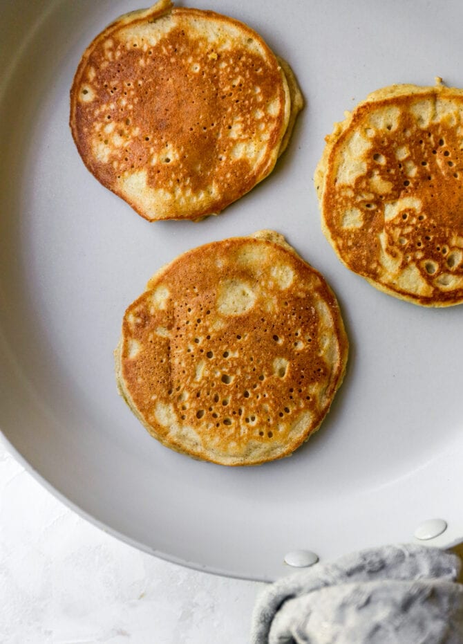 Three almond flour pancakes in a frying pan.