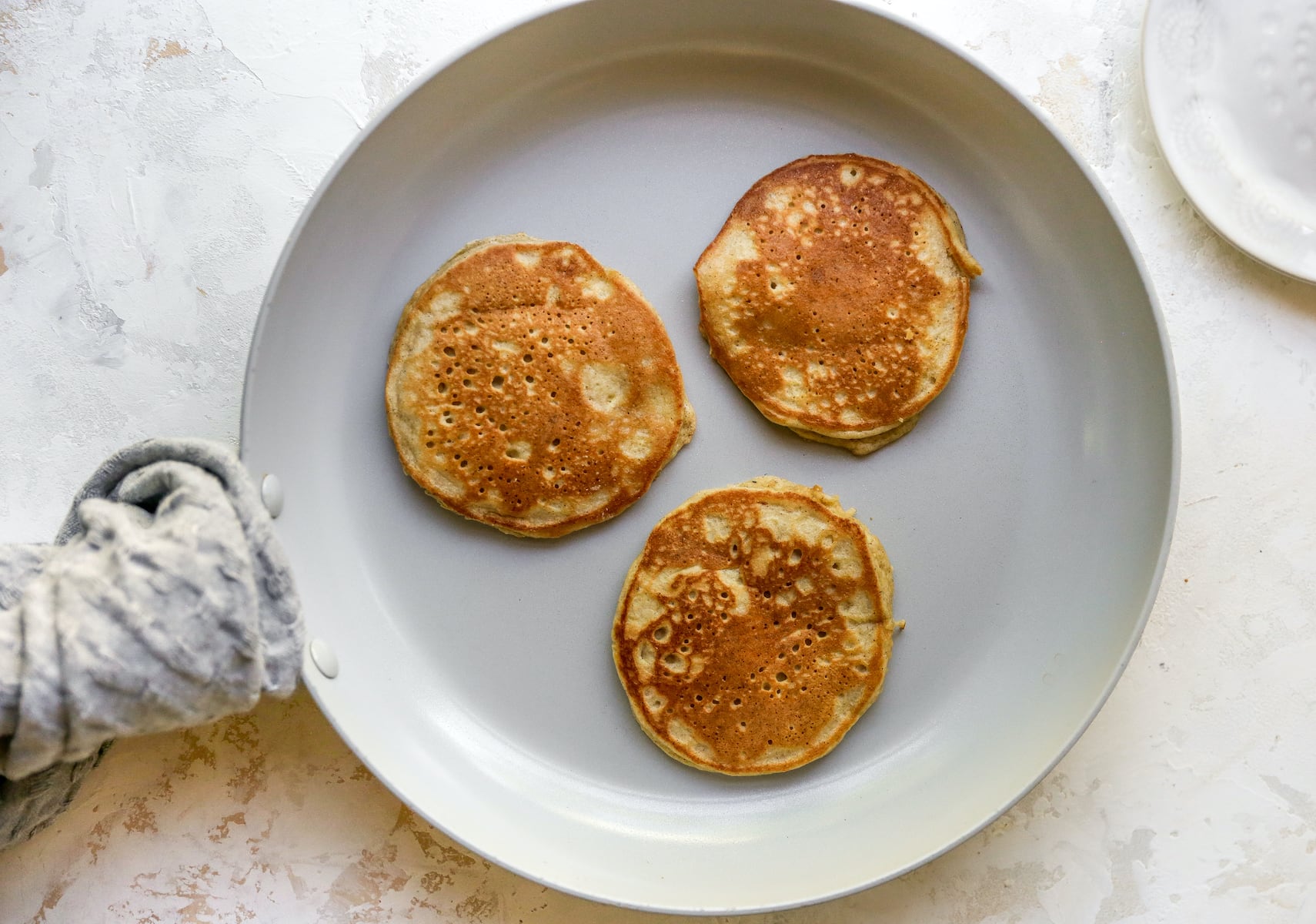 Three almond flour pancakes in a frying pan.