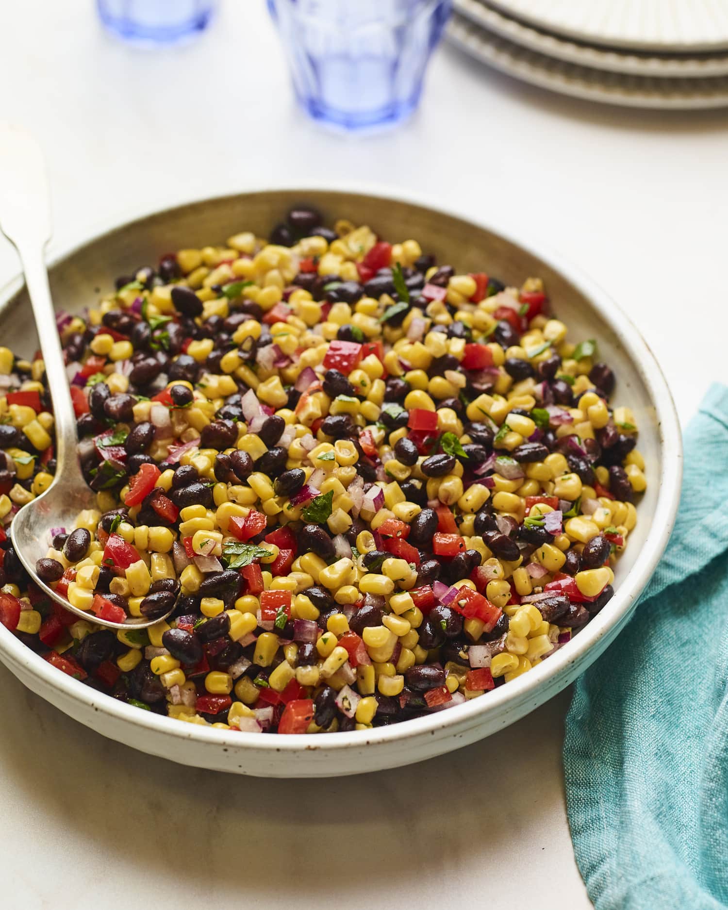 Serving bowl with black bean and corn salad. Spoon is in the bowl.