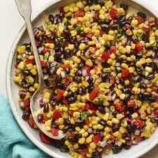 Serving bowl with black bean and corn salad. Spoon is in the bowl.