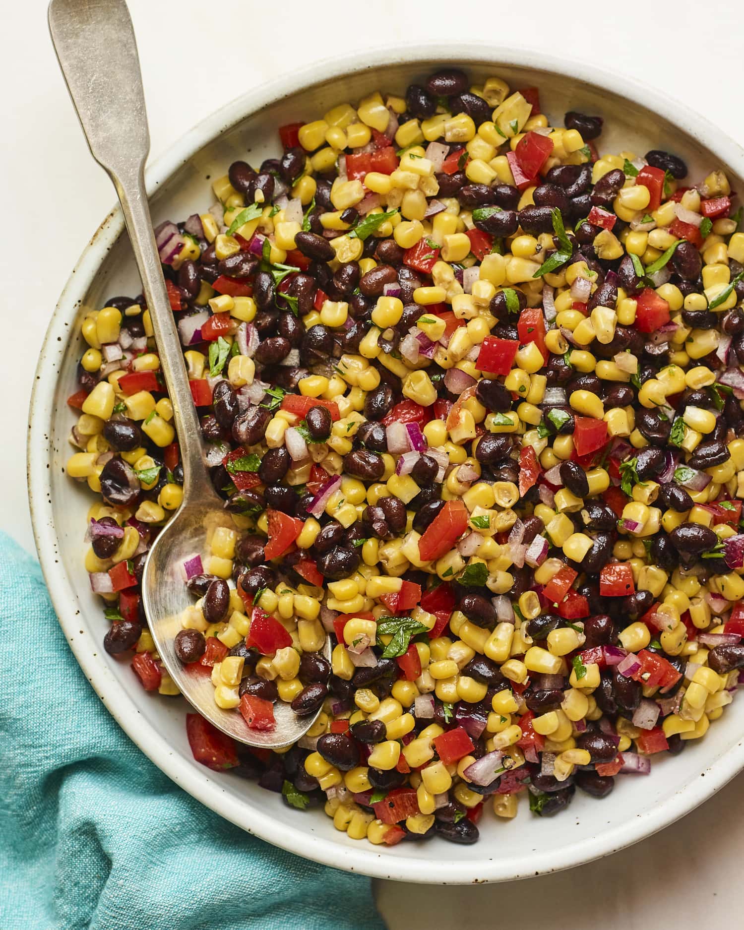 Serving bowl with black bean and corn salad. Spoon is in the bowl.