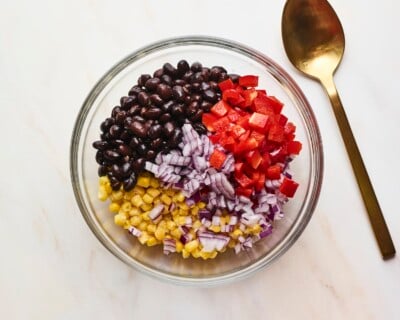 Mixing bowl with chopped pepper, onion, corn and black beans before being mixed.