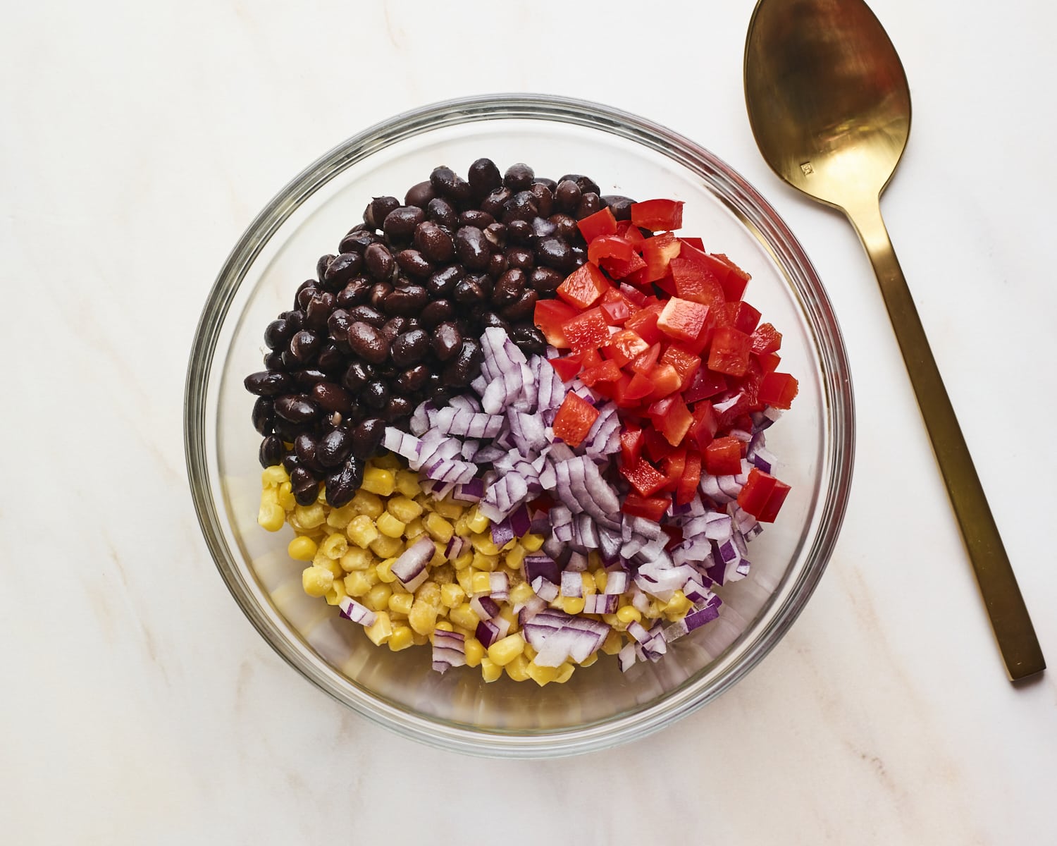 Mixing bowl with chopped pepper, onion, corn and black beans before being mixed.