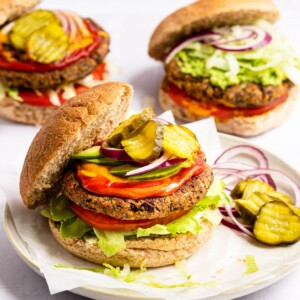 Black bean burger on a bun with lettuce, tomato, onion, ketchup, mustard and pickles.