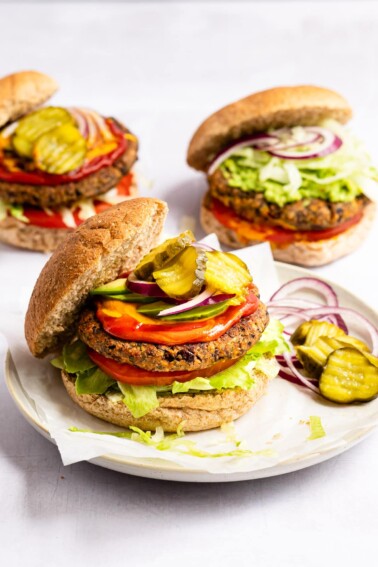 Black bean burger on a bun with lettuce, tomato, onion, ketchup, mustard and pickles.