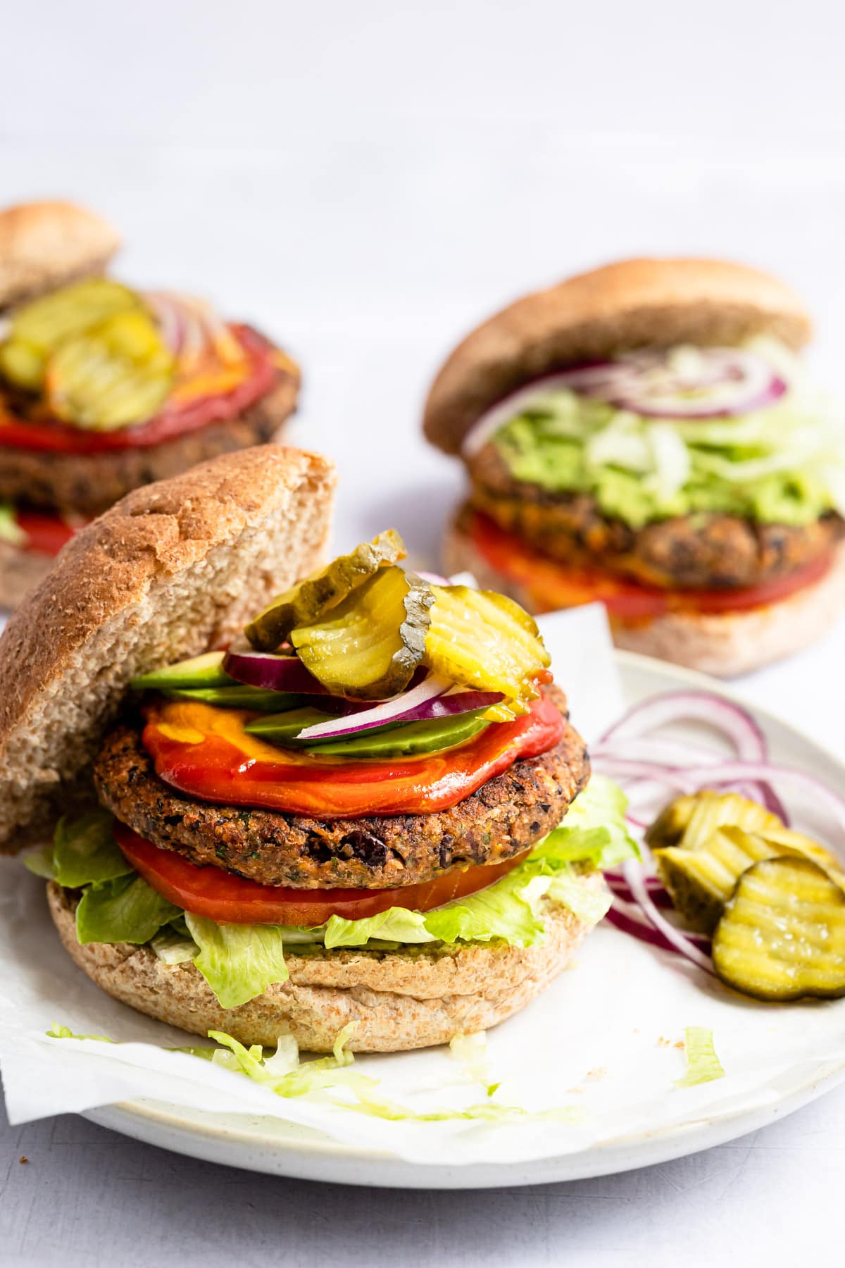 Black bean burger on a bun with lettuce, tomato, onion, ketchup, mustard and pickles.