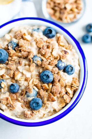 Blueberry overnight oats in a white and blue bowl with oatmeal crumble and blueberries on top.