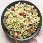 Serving bowl of cauliflower tabbouleh with a serving spoon.