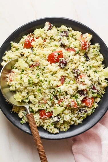 Serving bowl of cauliflower tabbouleh with a serving spoon.