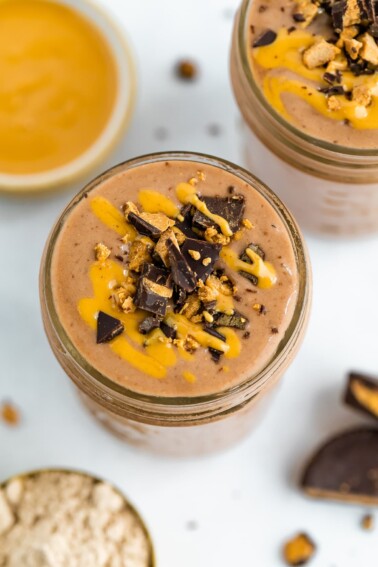 Chocolate smoothie with peanut butter drizzle and chopped peanut butter cup on top.