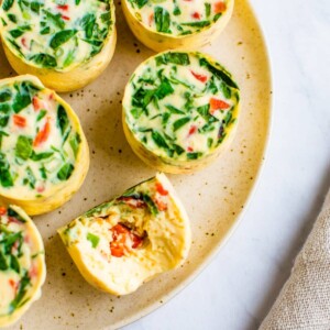 Veggie egg white bites on a plate. One has a bite taken out of it.