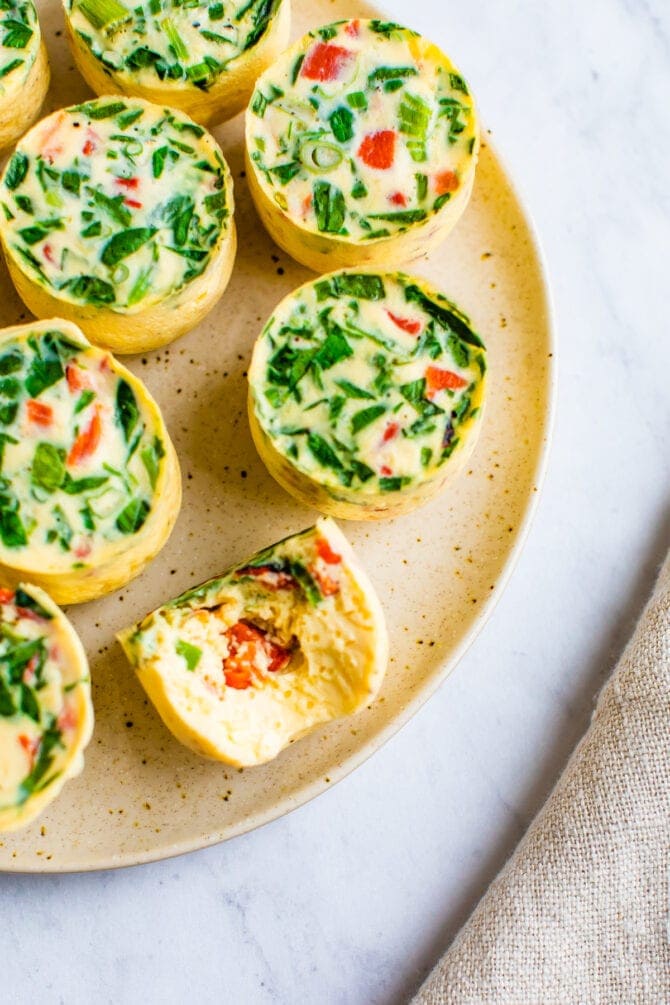 Veggie egg white bites on a plate. One has a bite taken out of it.