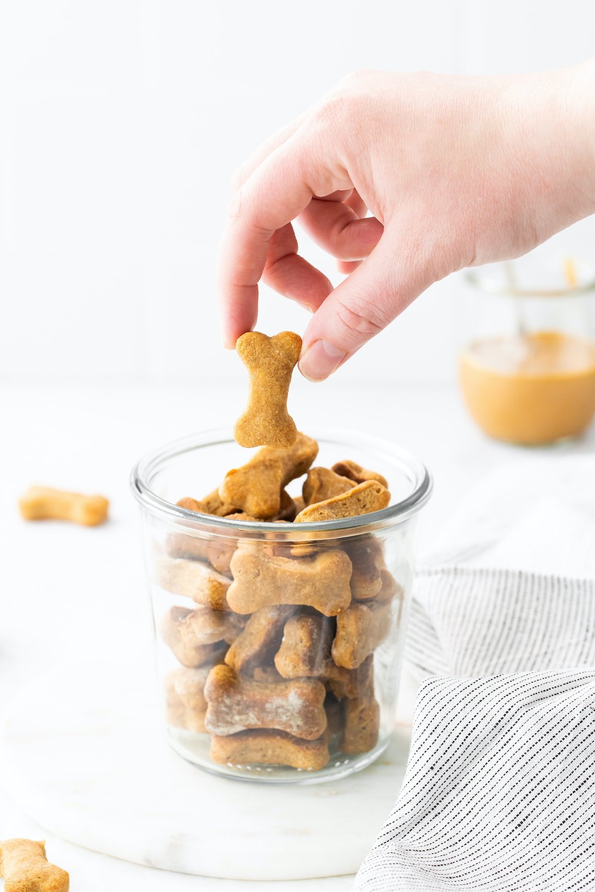 Hand picking up a homemade dog treat out of a jar.