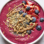 Smoothie bowl topped with berries, granola and almond butter.