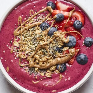 Smoothie bowl topped with berries, granola and almond butter.