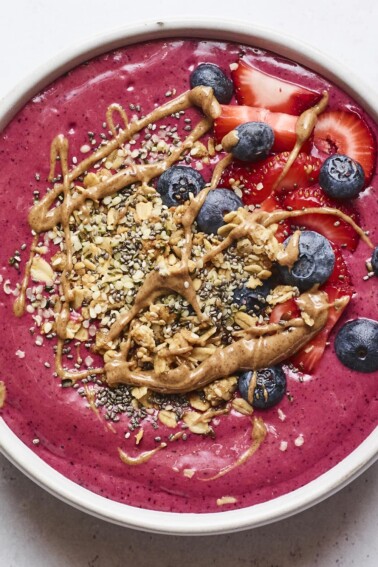 Smoothie bowl topped with berries, granola and almond butter.