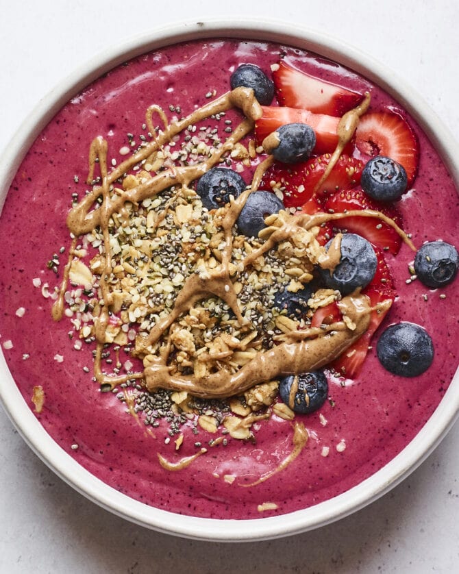 Smoothie bowl topped with berries, granola and almond butter.