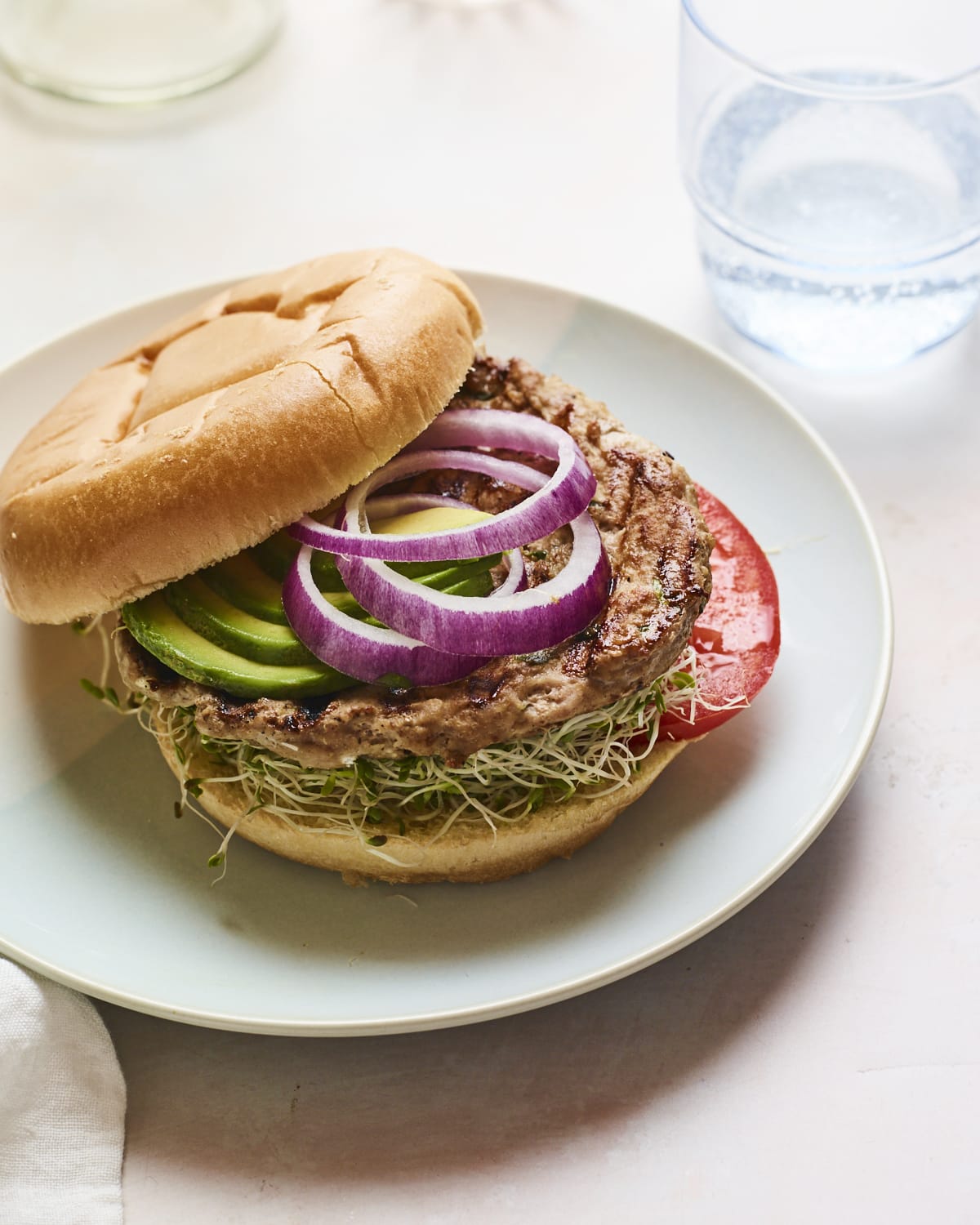 Spinach and feta turkey burger on a bun with avocado, onions, tomatoes and sprouts.