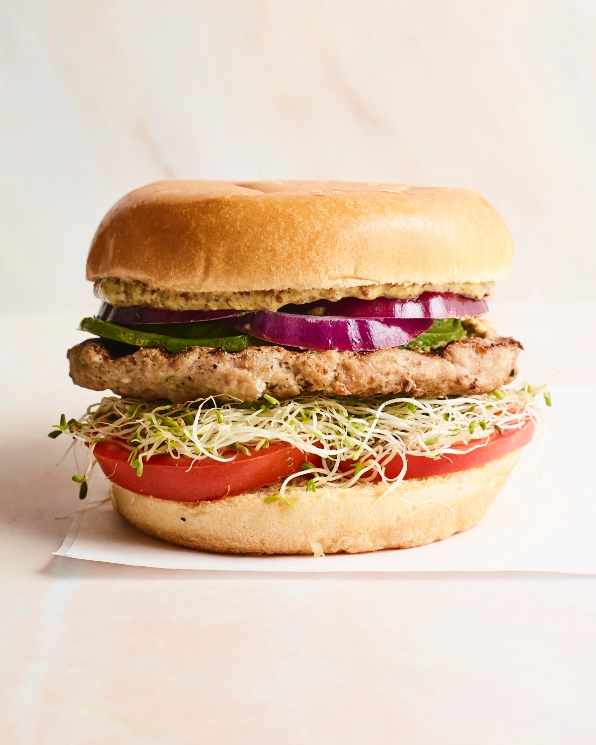 Spinach and feta turkey burger on a bun with avocado, onions, tomatoes and sprouts.