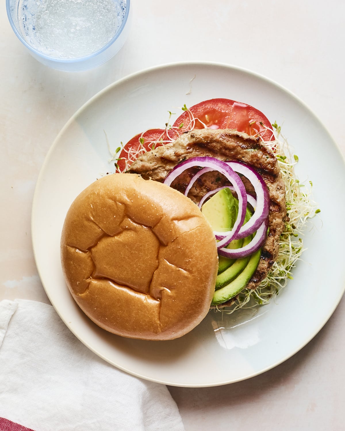 Spinach and feta turkey burger on a bun with avocado, onions, tomatoes and sprouts.