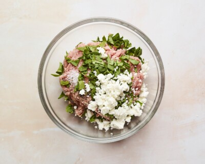 Mixing bowl with ground turkey and feta and spinach added on top.