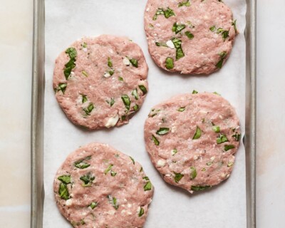 Four spinach and feta turkey burger patties on a sheet pan.