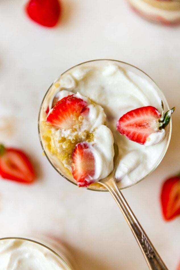 Spoon taking a bite out of a strawberry yogurt quinoa parfait.