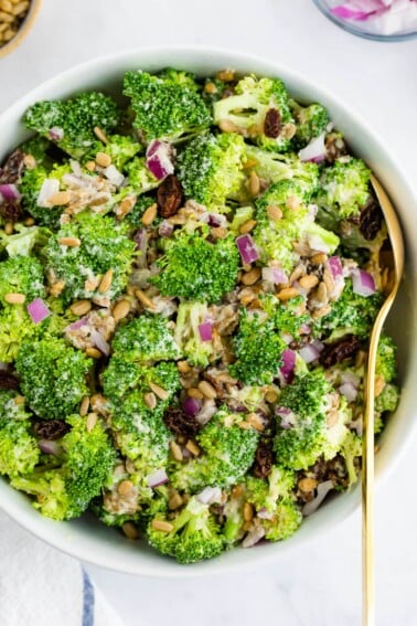 Overhead close up of vegan broccoli salad in a white bowl.