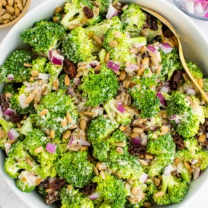 Overhead close up of vegan broccoli salad in a white bowl.