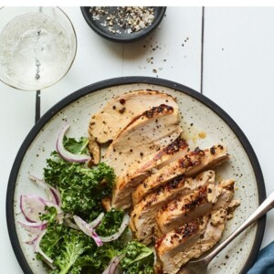 Plate of sliced grilled chicken and green veggies.